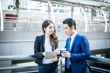 İş arkadaşları birlikte ofise yürürken tabletteki işlere bakarlar..