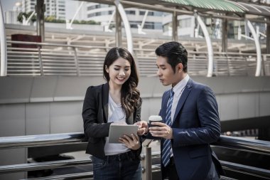 İş arkadaşları birlikte ofise yürürken tabletteki işlere bakarlar..