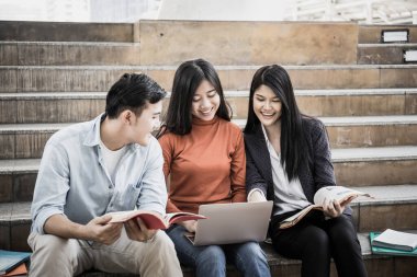 Grup öğrencileri laptopta araştırma yapıyor. Üniversitede birlikte oturuyorlar..