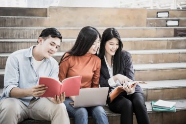 Grup öğrencileri laptopta araştırma yapıyor. Üniversitede birlikte oturuyorlar..