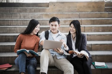 Grup öğrencileri laptopta araştırma yapıyor. Üniversitede birlikte oturuyorlar..