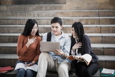 Grup öğrencileri laptopta araştırma yapıyor. Üniversitede birlikte oturuyorlar..