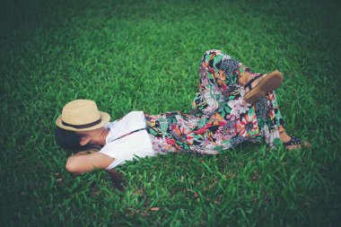 Genç bir kadın çimlere uzanıyor. Rahatlama zamanı.