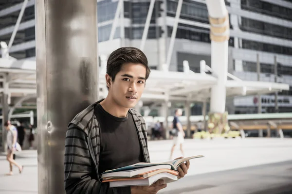 Erkek öğrenci dışarıda kitap okuyor. Yakışıklı genç adam kitap okuyor..