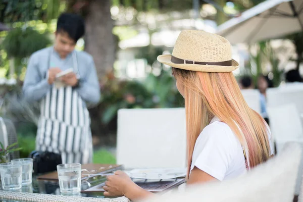 Smiling Young woman in a restaurant with the menu in hands, Young Woman Choosing from a Restaurant Menu