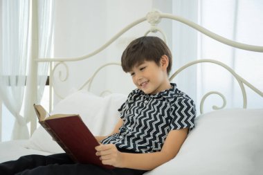 Genç çocuk evde yatakta kitap okuyor..