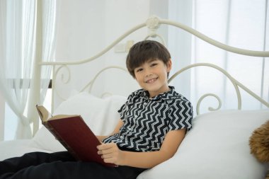 Genç çocuk evde yatakta kitap okuyor..