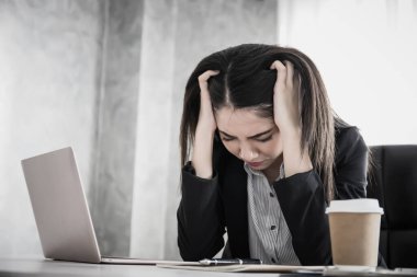 İş yerinde yeni bir projeyle düşünürken ellerinin başının üzerinde strese giren kadınlar