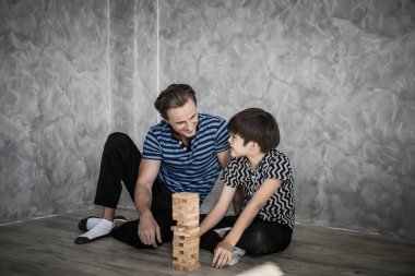 Baba ve oğul evde Jenga oynuyorlar. Mutlu aile kavramı.