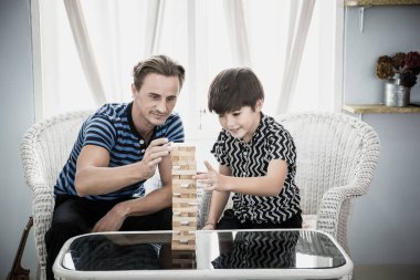 Baba ve oğul evde Jenga oynuyorlar. Mutlu aile kavramı.