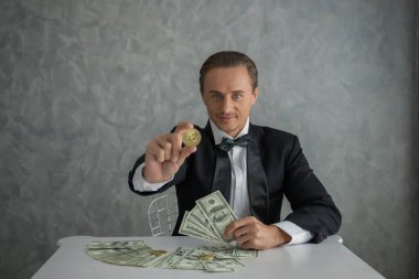 Bir dolar banknot parasıyla altın Bitcoin elinde tutan bir iş adamı. Dijital para kavramı