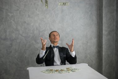 Etrafına düşen dolarlara bakan bir iş adamı.