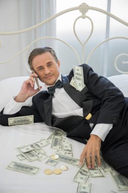 Dolar banknotlarıyla yatakta yatan zengin bir adam. Başarı iş konsepti.