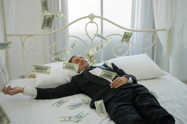 Rich man lying on the bed with dollar banknotes. Success business concept.