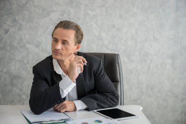 İşadamı iş yerinde bilgisayarının önünde oturmuş evrak işleriyle uğraşıyor..