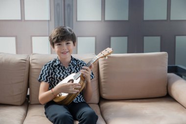 Küçük çocuk akustik gitar çalmayı öğreniyor.