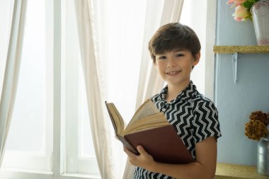 Çocuk odada kitap okuyor.