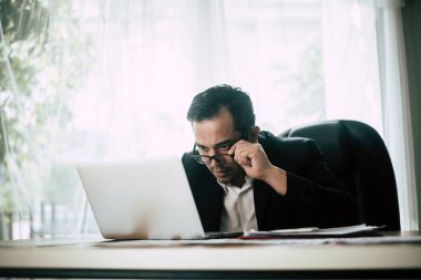 Belgeler üzerinde çalışan ciddi bir işadamı masadaki verileri ve planlama işlerini inceliyor..