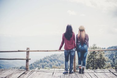 Kadın dışarıda rahatlıyor. Mutlu görünüyor ve gülümsüyor.