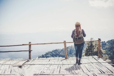 Kadın dışarıda rahatlıyor. Mutlu görünüyor ve gülümsüyor.