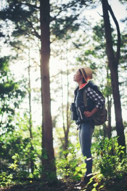 Dürbünlü bir kadın ormanda yürüyor. 
