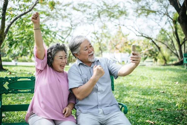 シニアカップルは公園でスマートフォンで自撮り写真を撮る — ストック写真