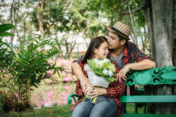若いカップルで自然のベンチに座って 男性と女性が一緒に — ストック写真