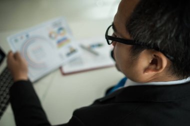 Genç işadamı ofiste dizüstü bilgisayarla çalışıyor.