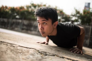 Dışarıda şınav çeken genç bir sporcunun yakın plan görüntüsü.