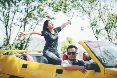 Üstü açık arabada mutlu çift.