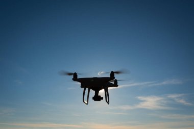 Beyaz dron açık mavi gökyüzünde süzülüyor