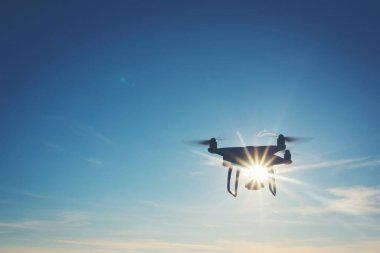 Beyaz dron açık mavi gökyüzünde süzülüyor