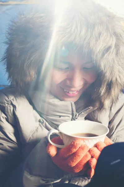 冬の公園でコーヒーを飲みながら笑顔の女性 — ストック写真