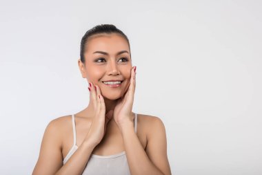 Temiz tenli güzel genç bir kadın, kendi yüzüne dokunur. 