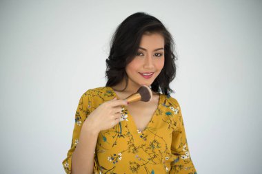 Genç, güzel bir kadın beyaz arka planda toz fırçasıyla dokunuyor