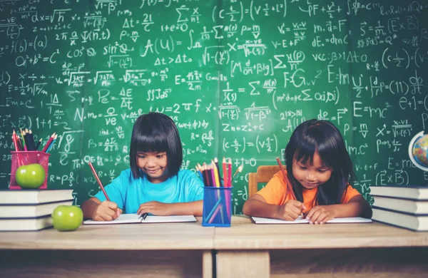 Two girl with crayon drawing at lesson in the classroom