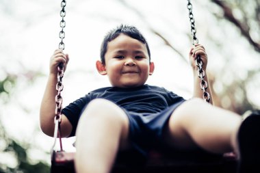 sevimli küçük çocuk açık salıncakta eğleniyor