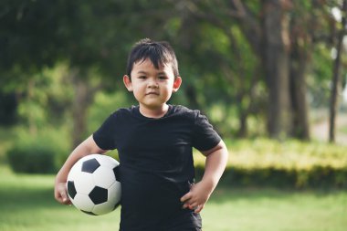 Küçük çocuk futbol topunu tutuyor.