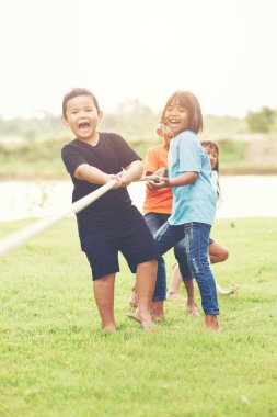 Çocuk grubu parkta çekiştirmece oynuyor.