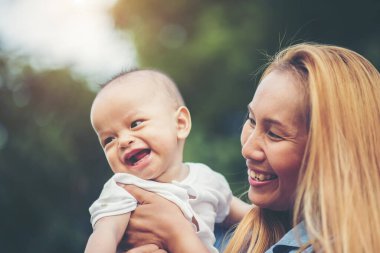 Annem bebeği kusuyor, gülüyor ve parkta oynuyor.