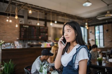 Genç bir kadın mutlu bir şekilde akıllı telefon kullanıyor ve bakıyor.