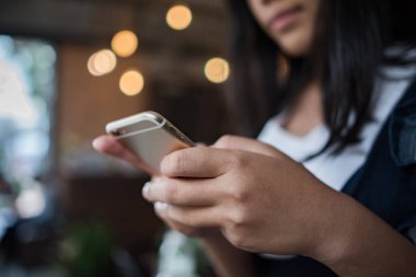 Genç bir kadın mutlu bir şekilde akıllı telefon kullanıyor ve bakıyor.