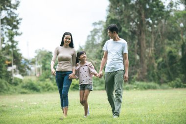Mutlu ebeveynler ve kızları parkta yürüyor. Mutlu aile kavramı..
