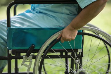 Hastanedeki bahçede tekerlekli sandalyede oturan yalnız yaşlı kadını kapat.