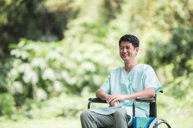 Bahçede tekerlekli sandalyede yalnız genç bir adam var.