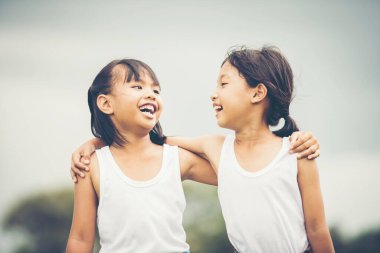 İki küçük kız el ele tutuşup parkta eğleniyorlar.