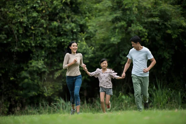 Mutlu aile eğleniyor. Anne, baba ve kız parkta koşuyorlar..