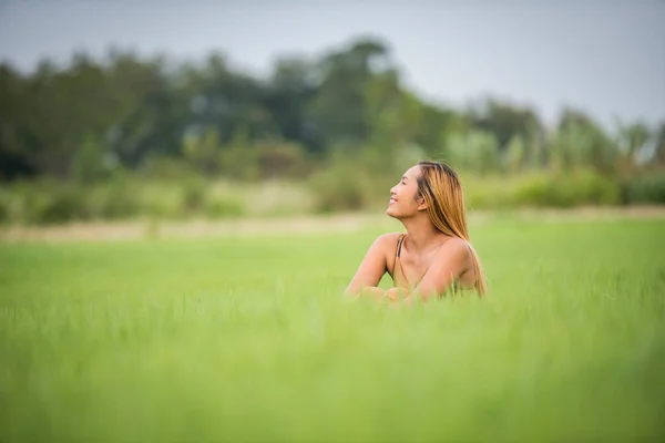 Young woman sitting feel good in grass field.