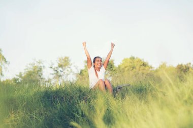 Çimenlerde oturan sırt çantalı bir turist kadın. 