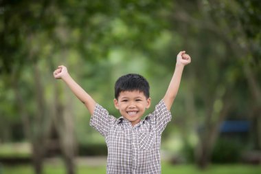 Doğanın bulanık arka planında doğayla el sıkışmaktan hoşlanan tatlı bir çocuk.. 